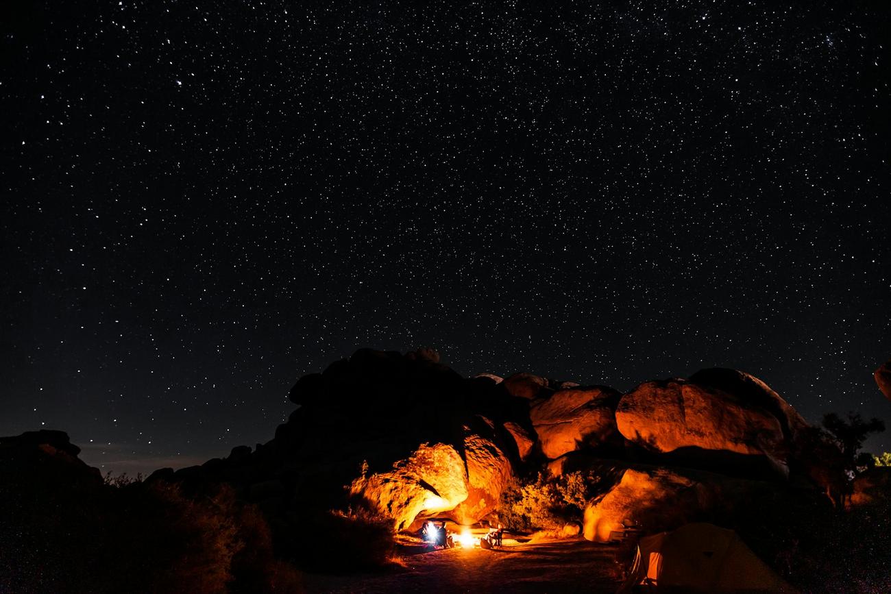 A campfire burning under a sky full of stars